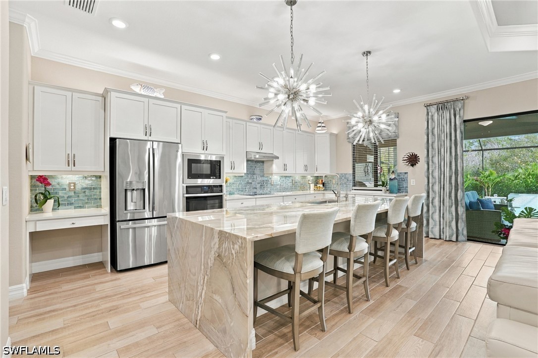 Kitchen with a large veined stone island, white cabinetry, and sliding doors to a patio.