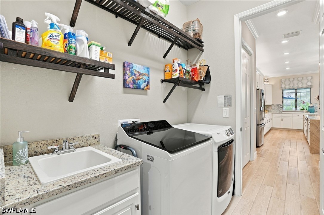 Laundry room with washer and dryer, a utility sink, and open shelves stocked with cleaning supplies.
