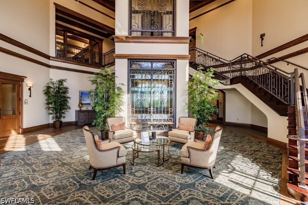 Spacious lobby with an ornate glass elevator, patterned tile floor, and sweeping dark wood staircase.