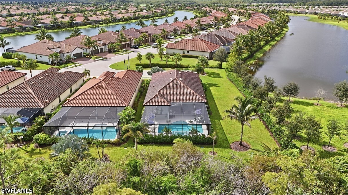 Aerial view of a home with a screened pool beside a lake in a Bonita Springs neighborhood.