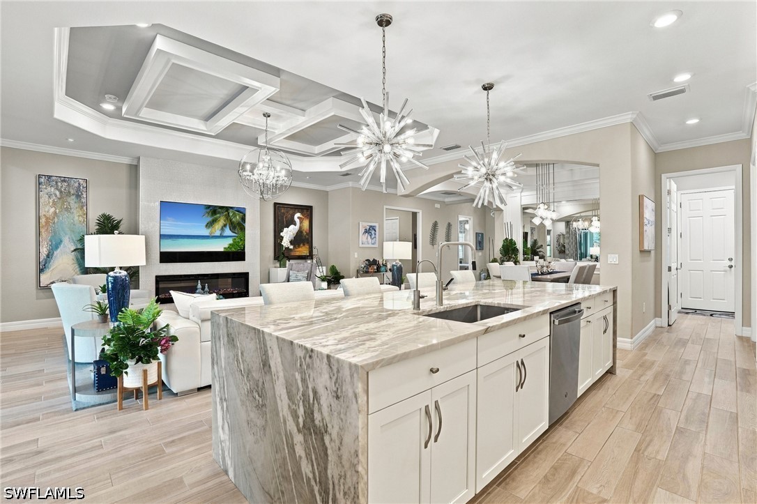 Open-plan kitchen with a large marble waterfall island, white cabinetry, and adjoining furnished living room.