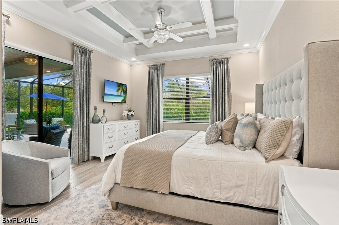 Bedroom with a tray ceiling, upholstered bed, and sliding doors opening to a covered patio.