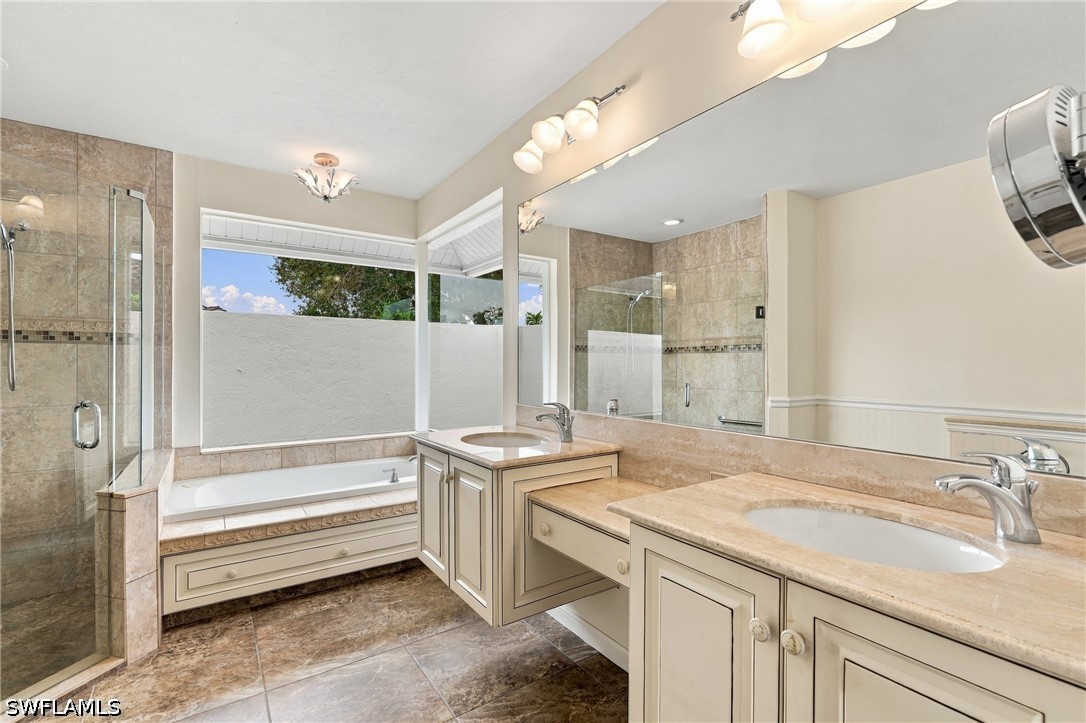 Bathroom with a dual-sink vanity, built-in soaking tub, and glass-enclosed shower.