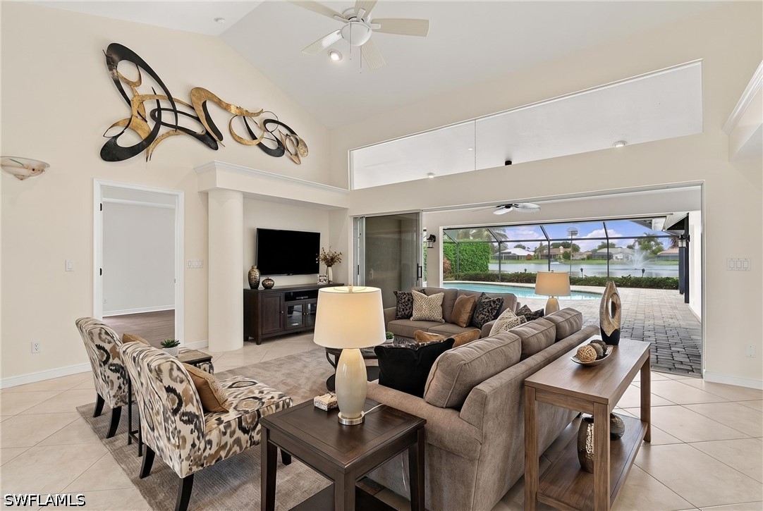 Living room with a sectional sofa and armchairs facing a screened lanai, pool, and water view.