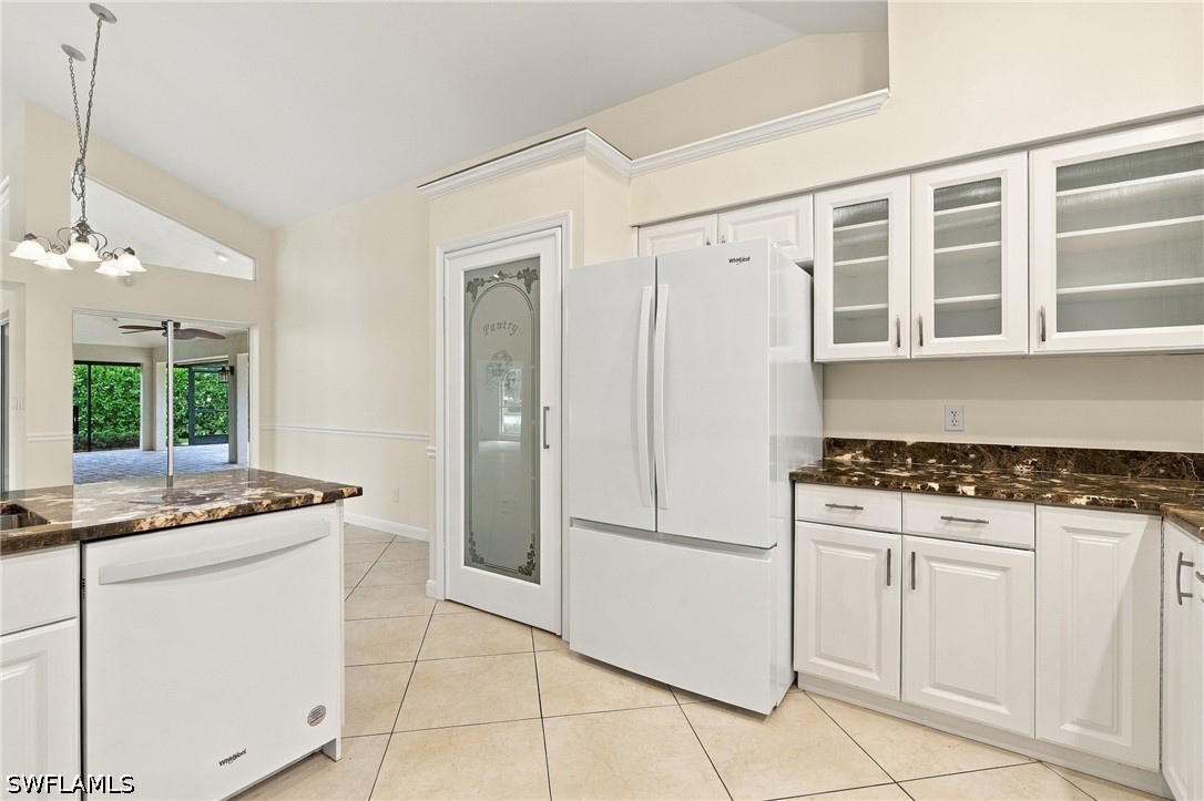 Kitchen with white cabinetry, dark stone counters, and a glass pantry door.
