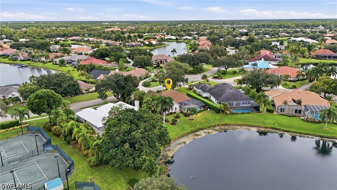 Aerial view of the home marked by a pin beside a lake, with tennis courts nearby.