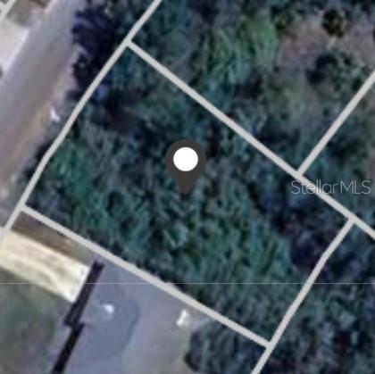 Aerial view of a wooded lot outlined by parcel boundaries, with a map pin marking its location.