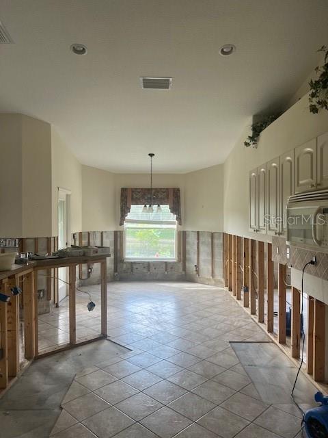 Vacant kitchen with tile floors, upper cabinets, and exposed framing along the lower walls.