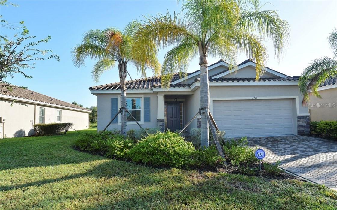 Single-story home with blue shutters, palm trees, and a two-car garage.