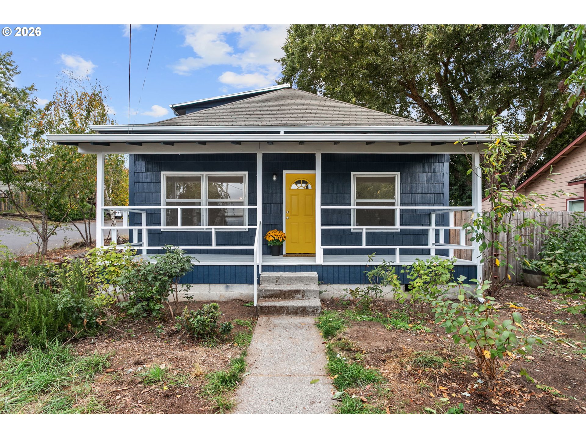 Blue house with a white-railed front porch and bright yellow door