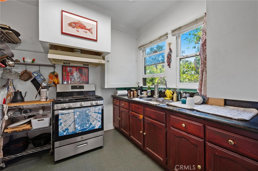 Kitchen with a stainless steel range, dark wood cabinets, and two bright windows above the sink.