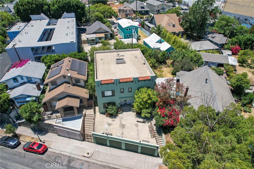 Aerial view of a green two-story building with a gated driveway among neighboring homes.