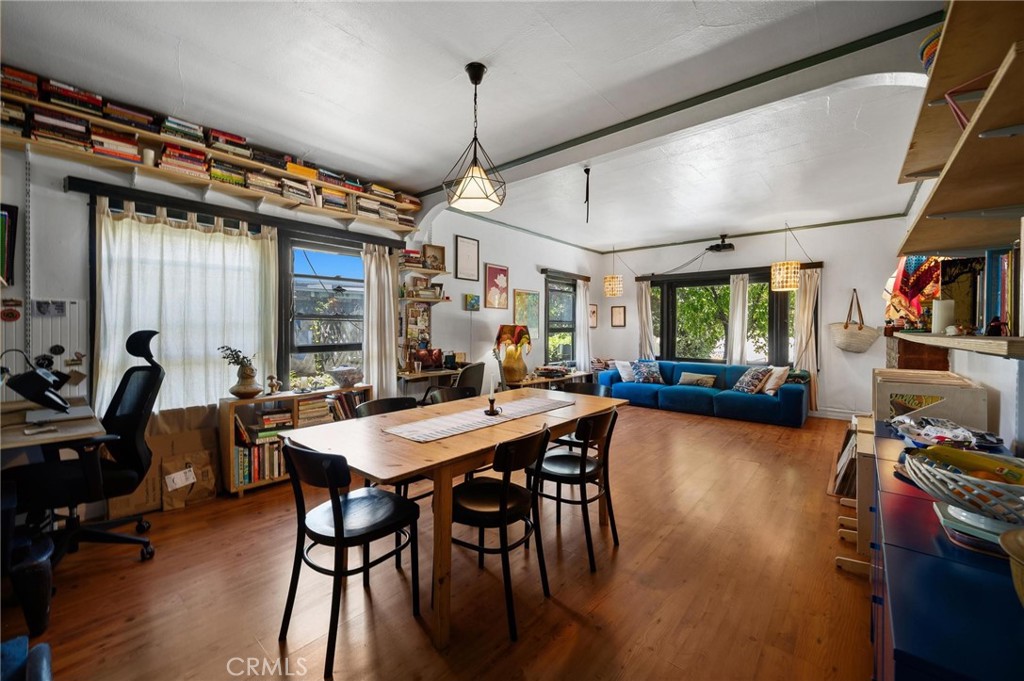 Open-plan living and dining room with a blue sofa, long wooden table, and wall-length bookshelves.
