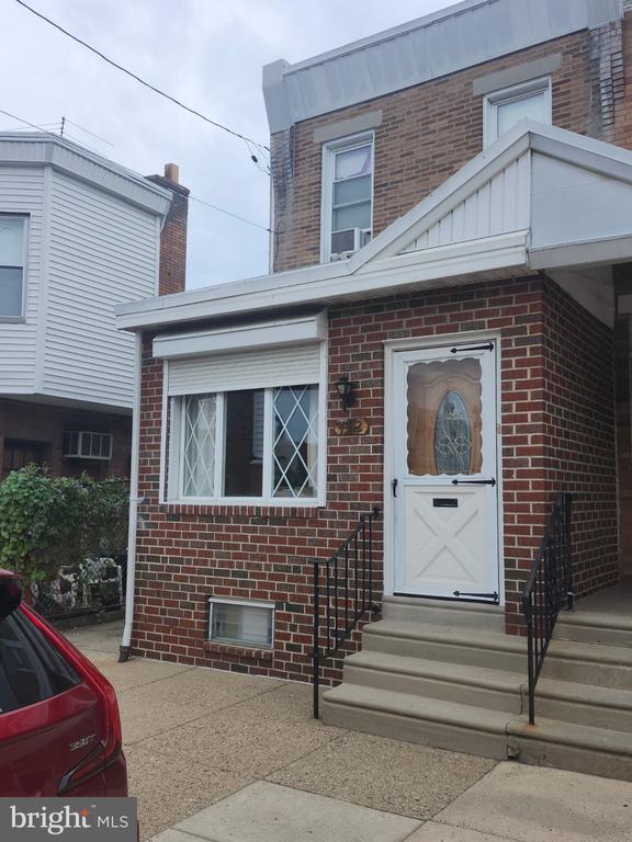 Brick home with a white entry door, front window, and concrete steps.