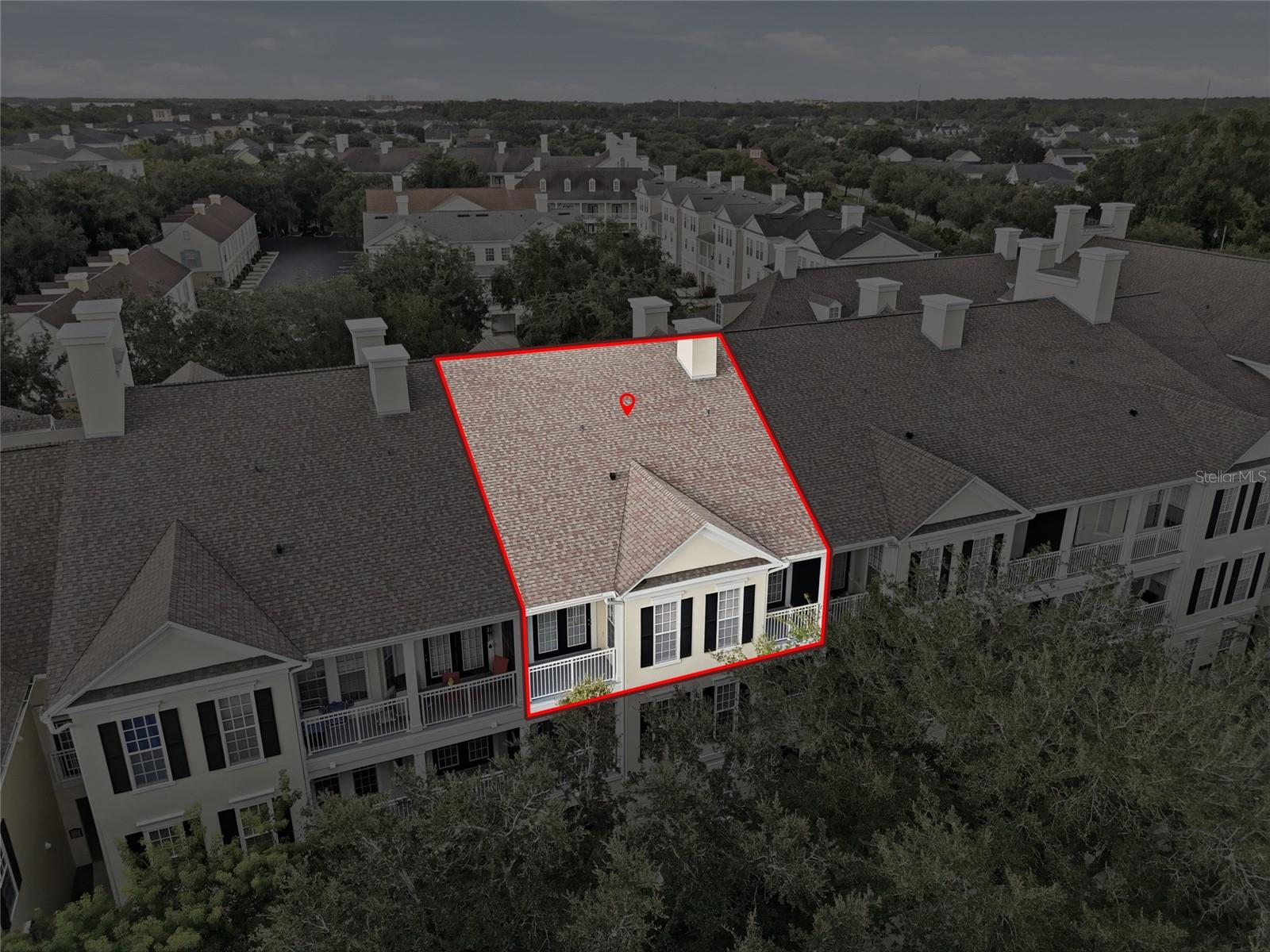 Aerial view of a townhouse unit outlined in red among a residential complex.