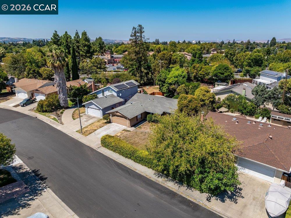 Aerial view of a single-story home with a gray roof on a tree-lined Concord street.