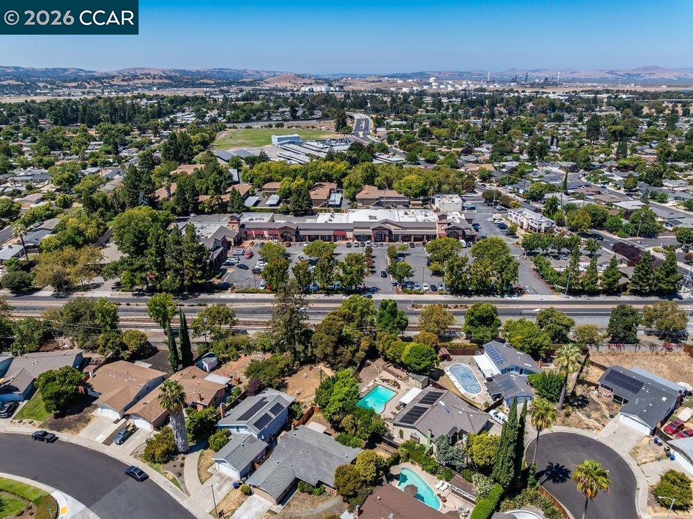 Aerial view of a Concord neighborhood with homes, swimming pools, and distant hills.