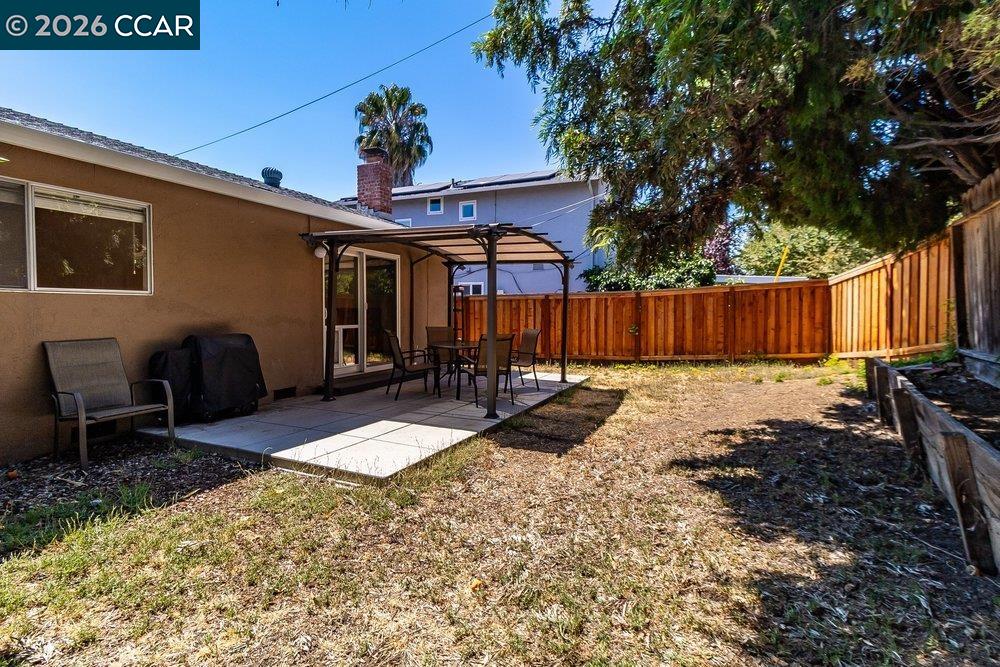 Fenced backyard with a paved patio, pergola, and outdoor dining set.