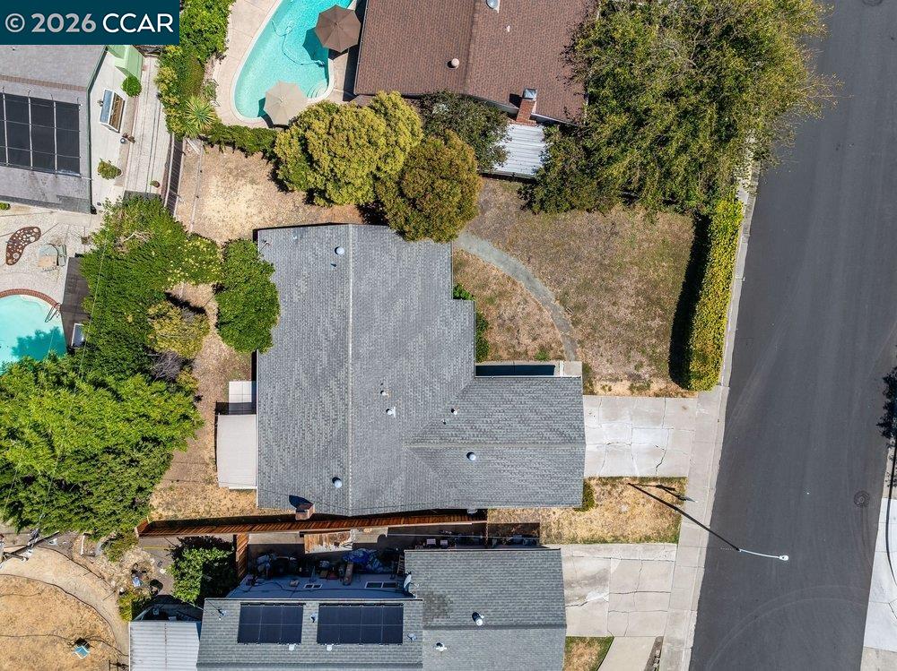 Aerial view of a gray-roofed home, front yard, and driveway beside the street.