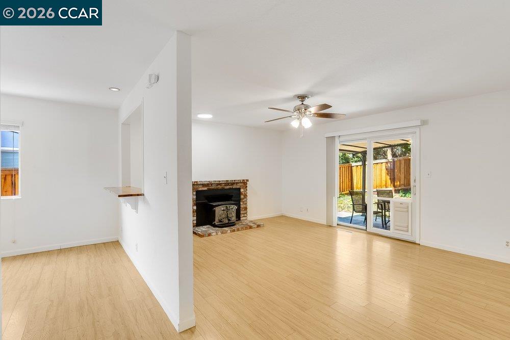 Vacant living room with a brick fireplace, light wood floors, and sliding doors to a patio.