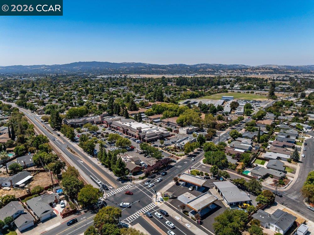 Aerial view of a Concord neighborhood with a busy intersection, shops, homes, and distant hills.