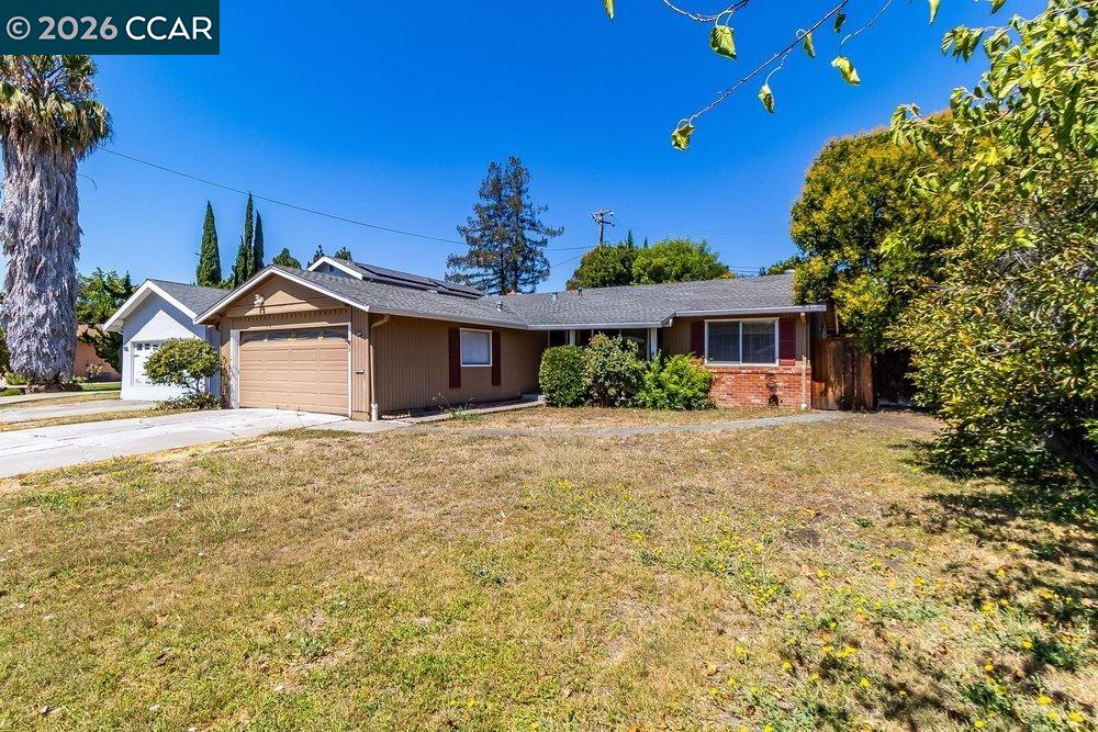 Single-story home with a two-car garage, brick accents, and a broad dry front lawn.