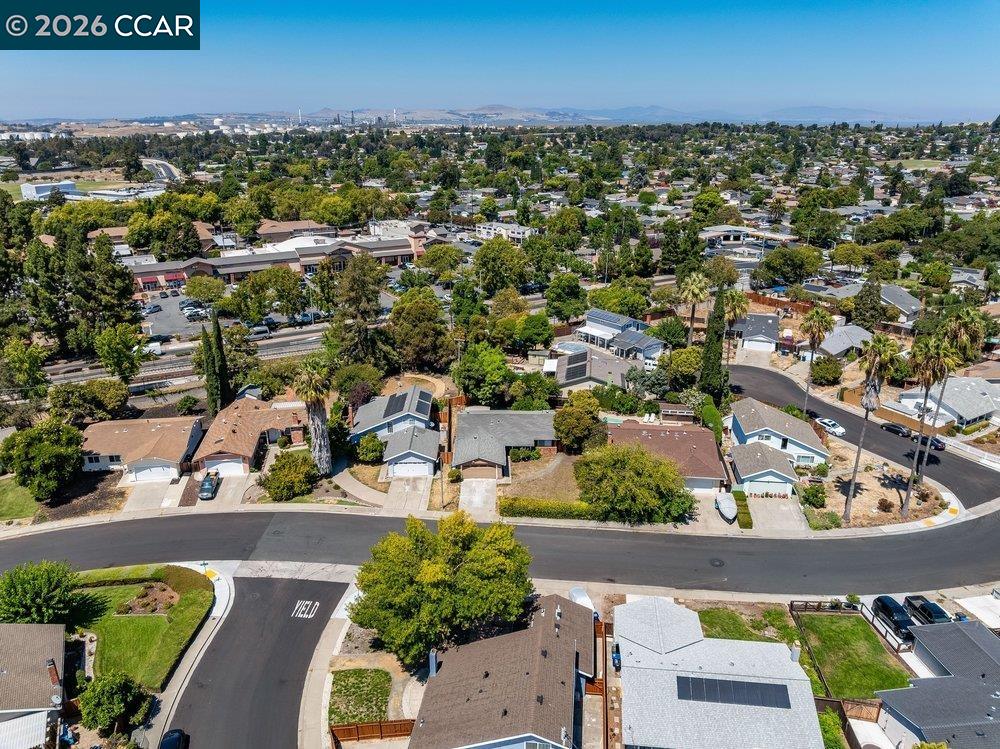 Aerial view of a Concord neighborhood with tree-lined streets and distant hills.
