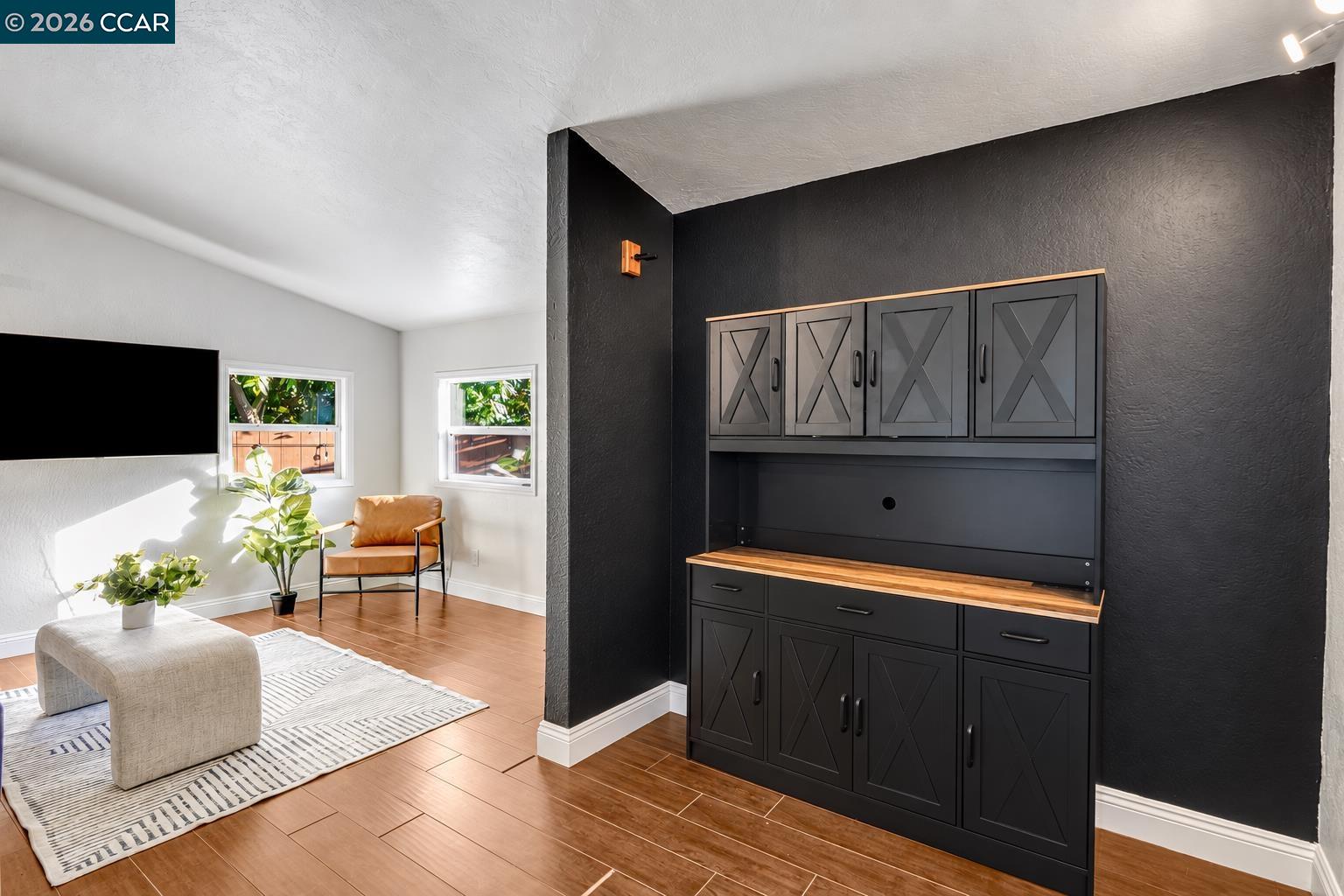 Living room with a black built-in cabinet, wood countertop, tan chair, and sunlit windows.