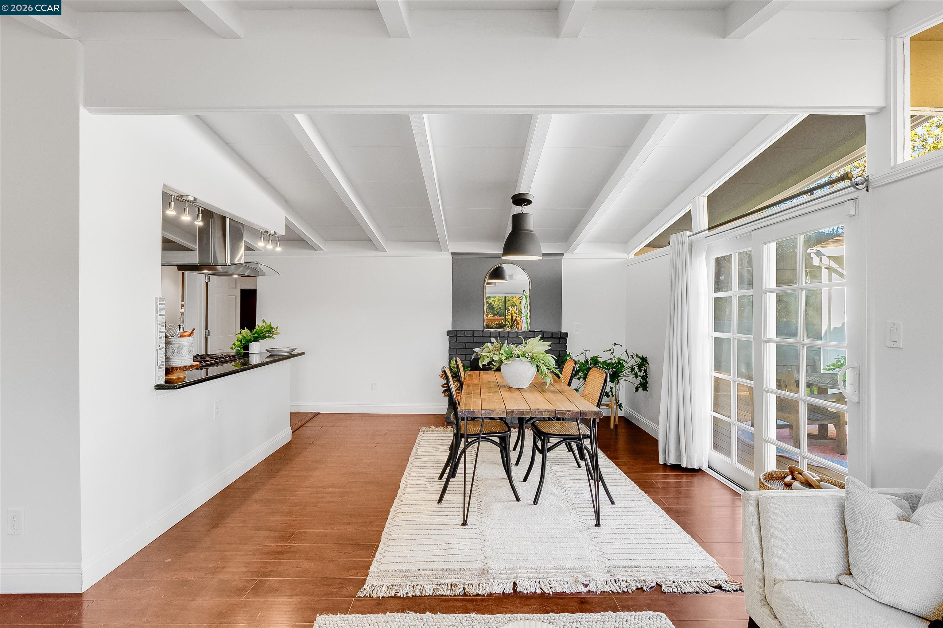 Staged dining room with a wooden table, black brick fireplace, and French doors opening to a deck.