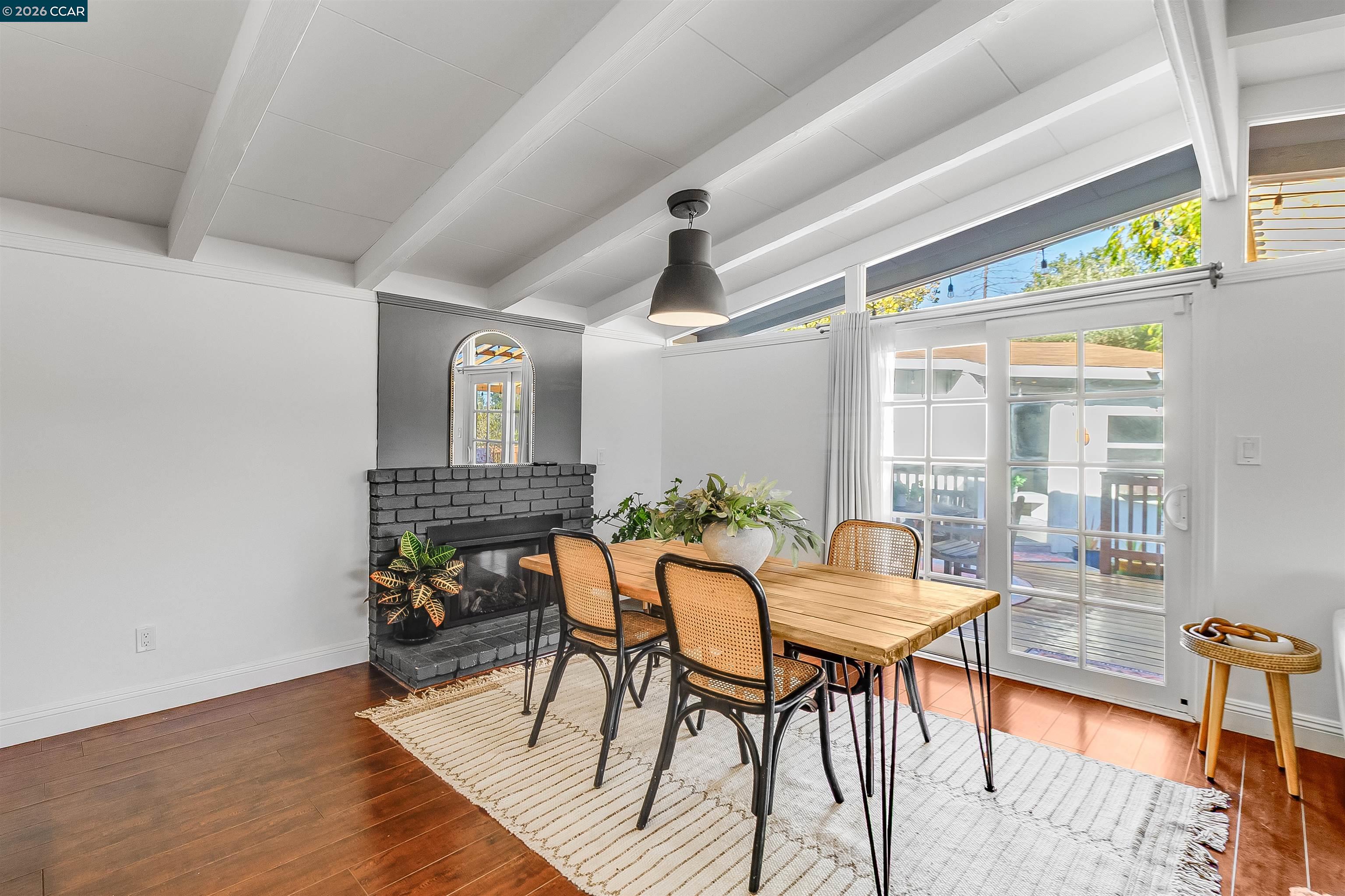 Dining room with a black brick fireplace, vaulted ceiling, and glass doors to a deck.