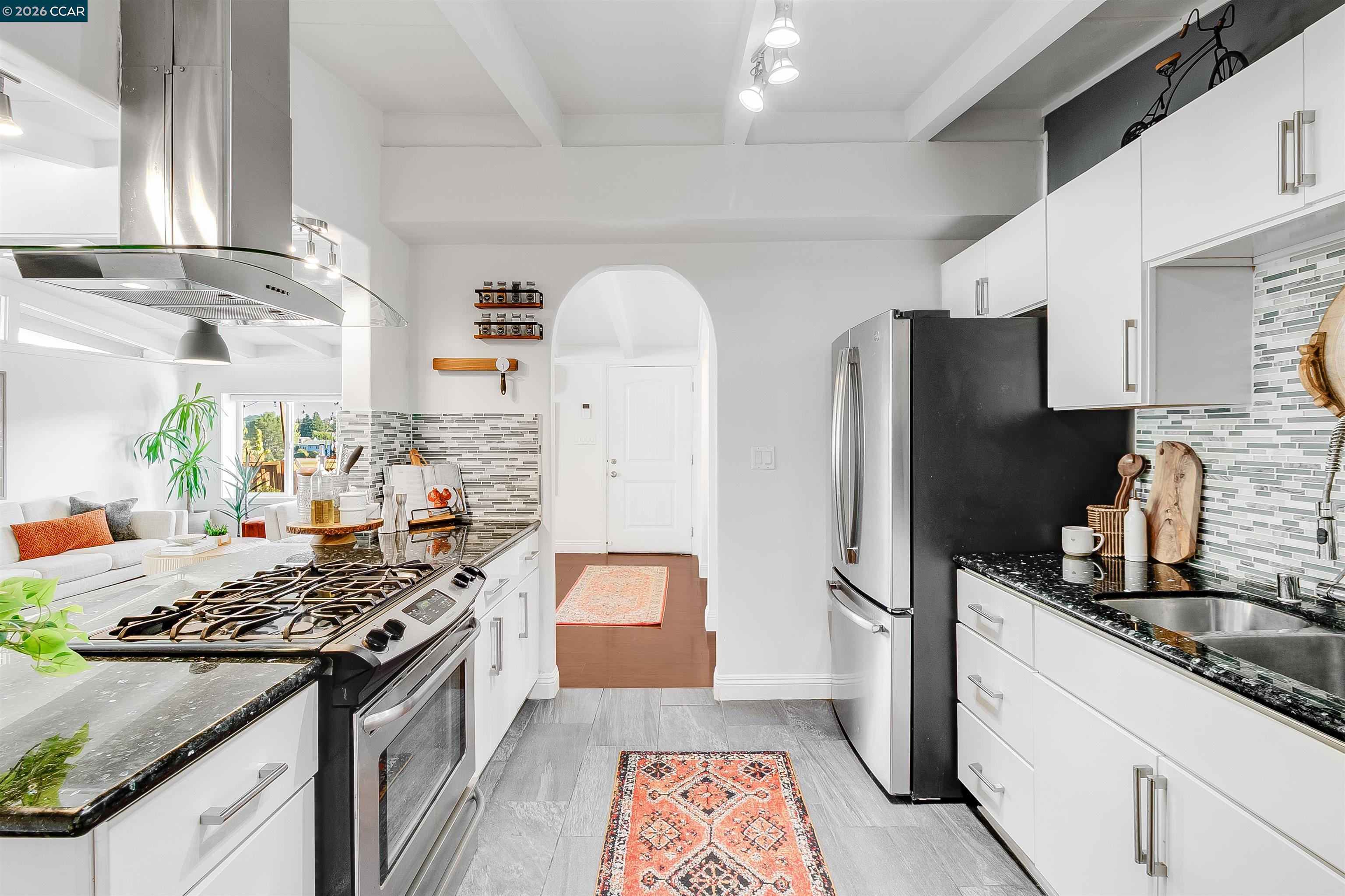 Bright white kitchen with stainless-steel appliances, a gas range, and patterned runners.
