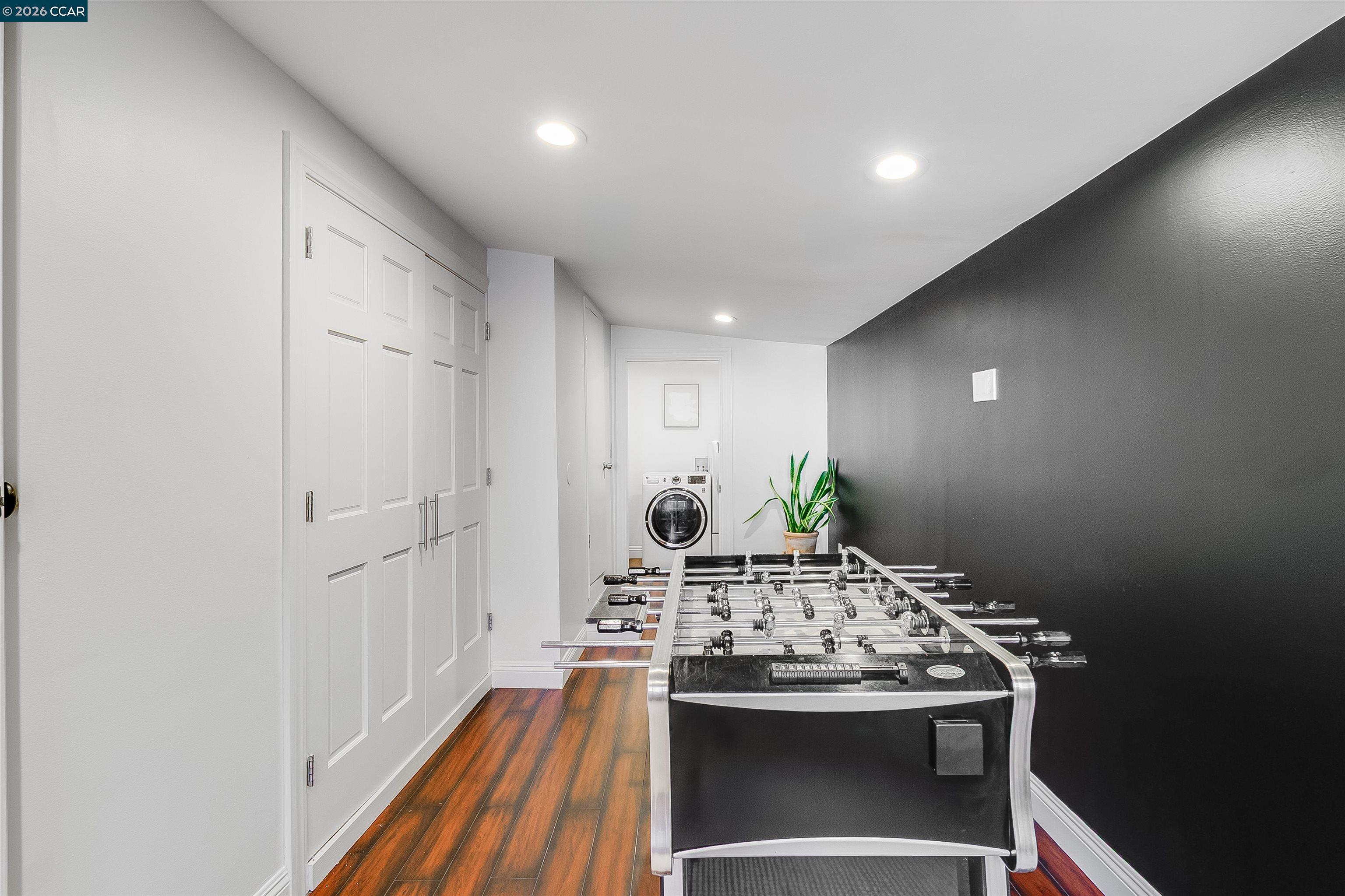 Game room with a foosball table, dark accent wall, and laundry machine at the back.