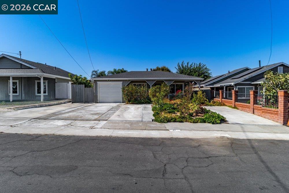 Single-story home with a front garage, wide concrete driveway, and landscaped planting beds.