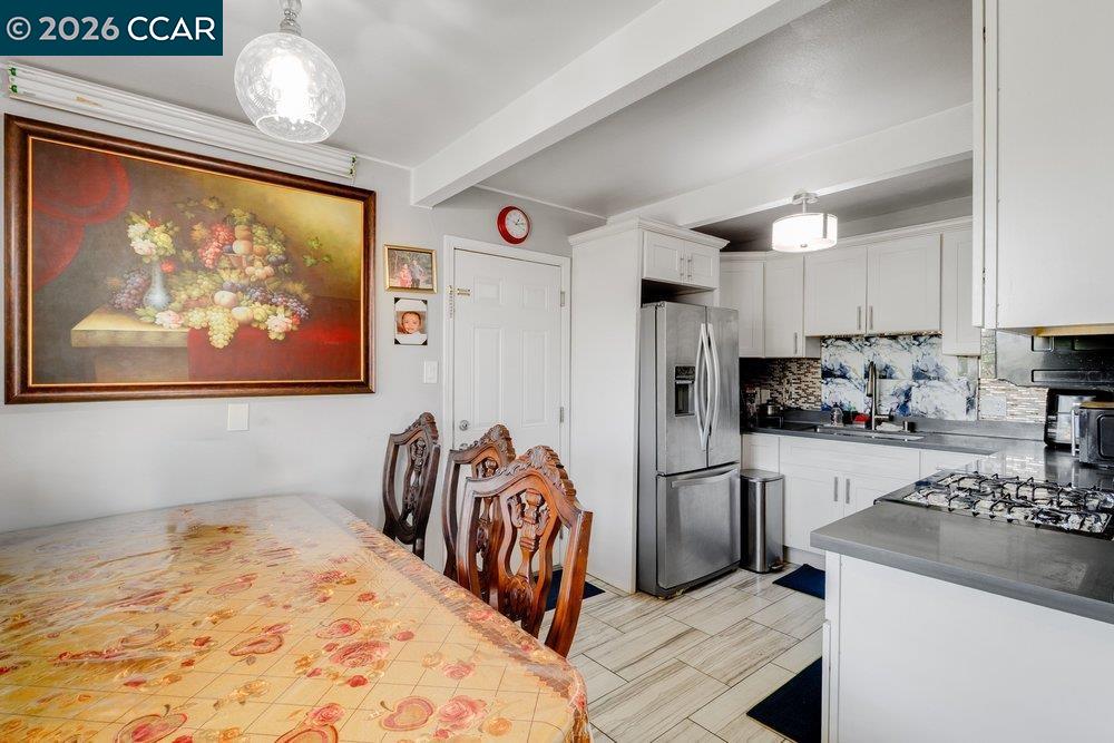 Kitchen and dining area with white cabinetry, stainless steel appliances, and a carved wooden dining set.