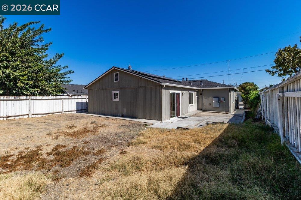 Rear exterior of a single-story home with a fenced, dry yard and concrete patio.