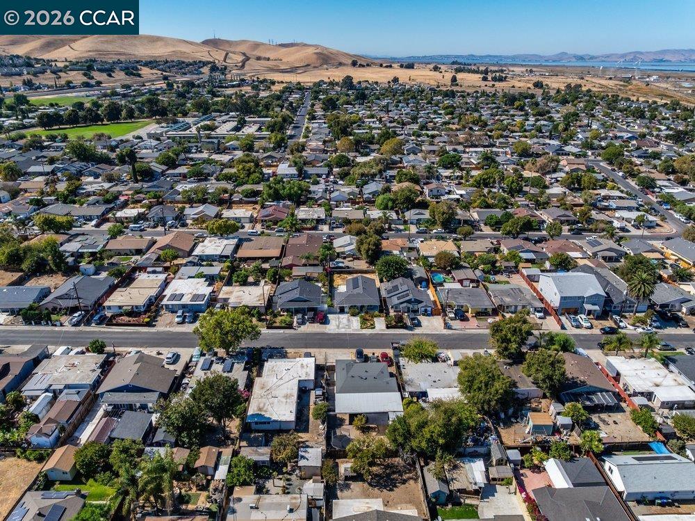Aerial view of a residential neighborhood, with rolling hills and water in the distance.