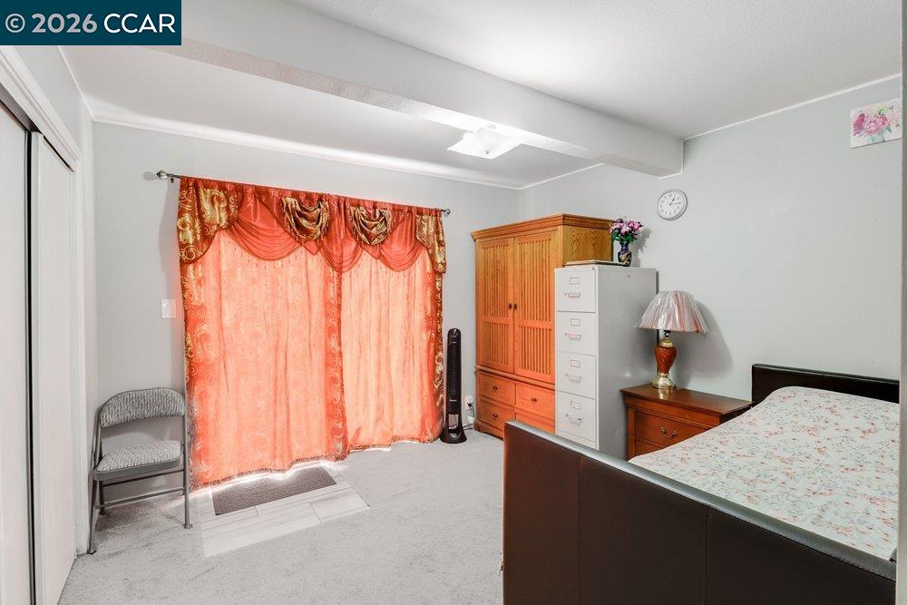 Bedroom with orange patterned curtains, a dark wood bed, and a wooden wardrobe.