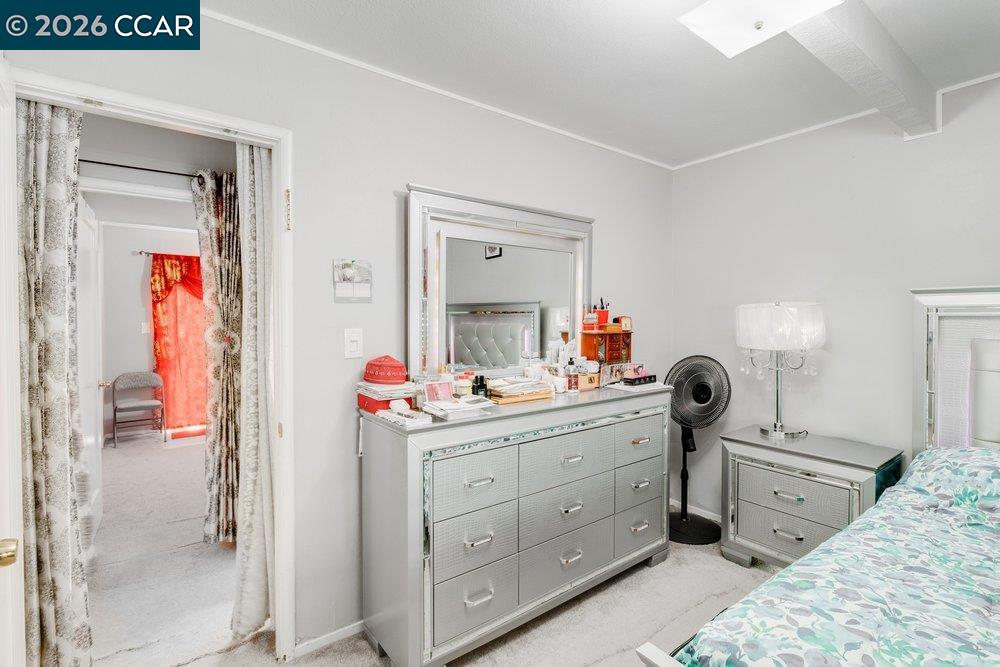 Bedroom with mirrored silver furniture, patterned bedding, and an open doorway.