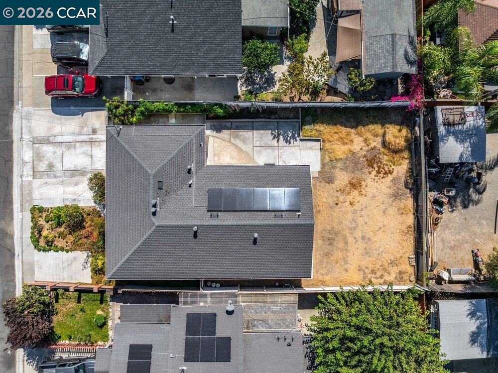 Aerial view of a home with rooftop solar panels and a dry backyard.