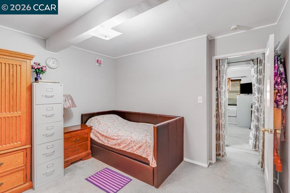 Bedroom with a single bed, wooden wardrobe, and purple striped rug.