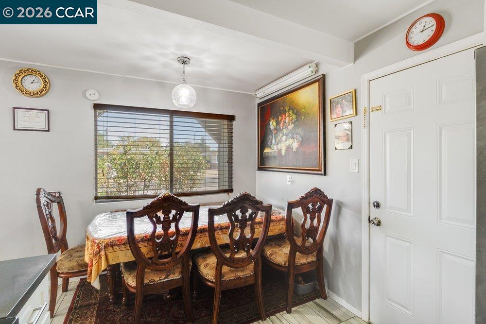 Dining room with carved wooden chairs, a patterned tablecloth, and a large window with blinds.