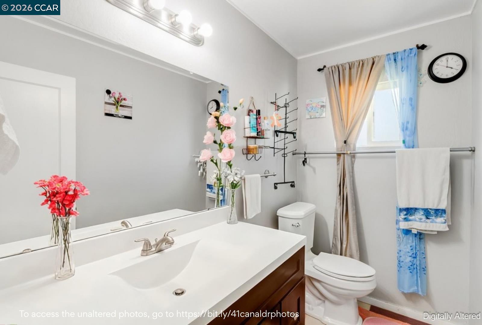 Bathroom with a white vanity sink, dark wood cabinets, and a toilet beside a curtained window.