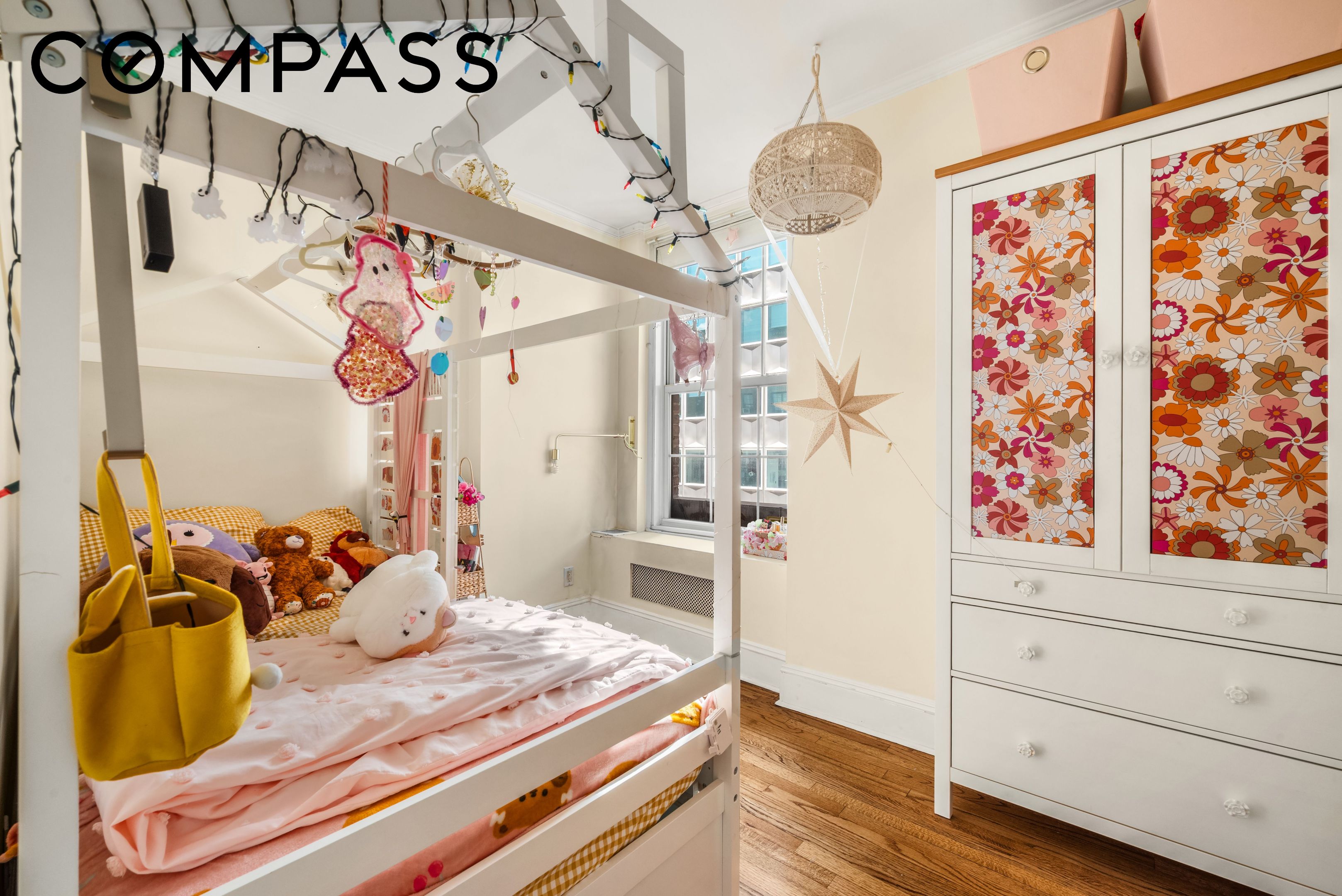 Children’s bedroom with a white bunk bed, pink bedding, plush toys, and floral wardrobe panels.