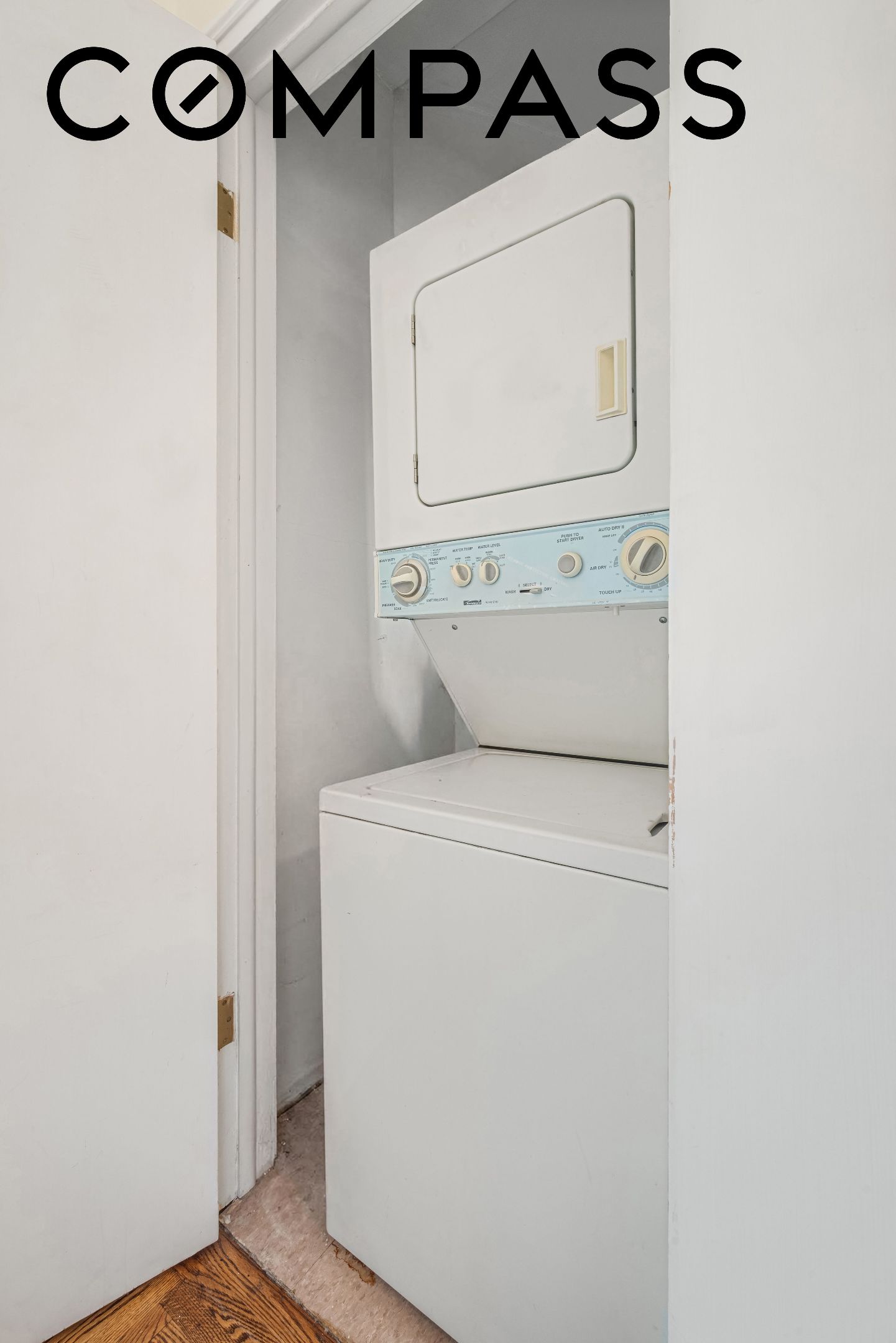 Stacked washer and dryer in a laundry closet behind an open doorway.