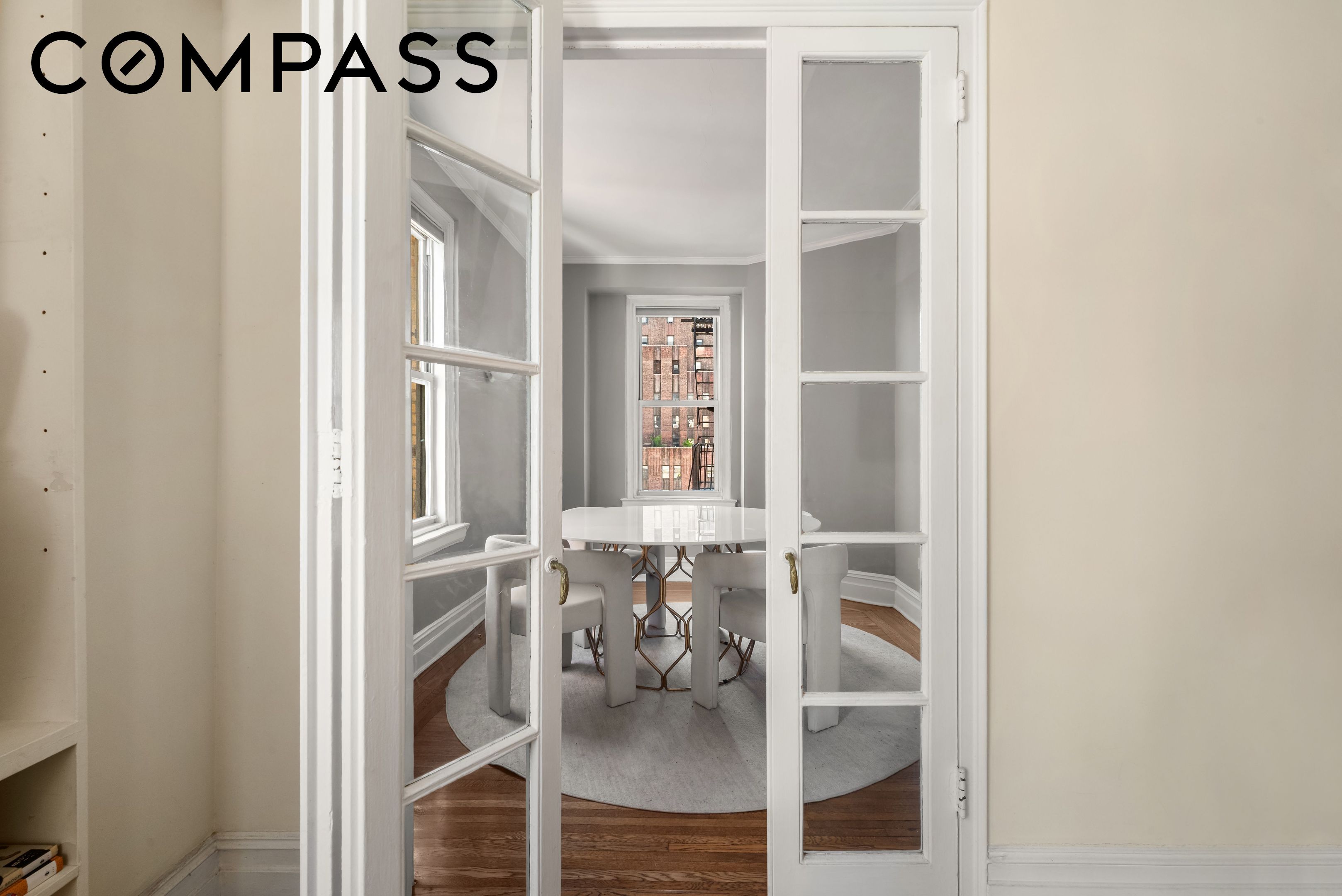 Dining room with white French doors, a round table, upholstered chairs, and hardwood floors.