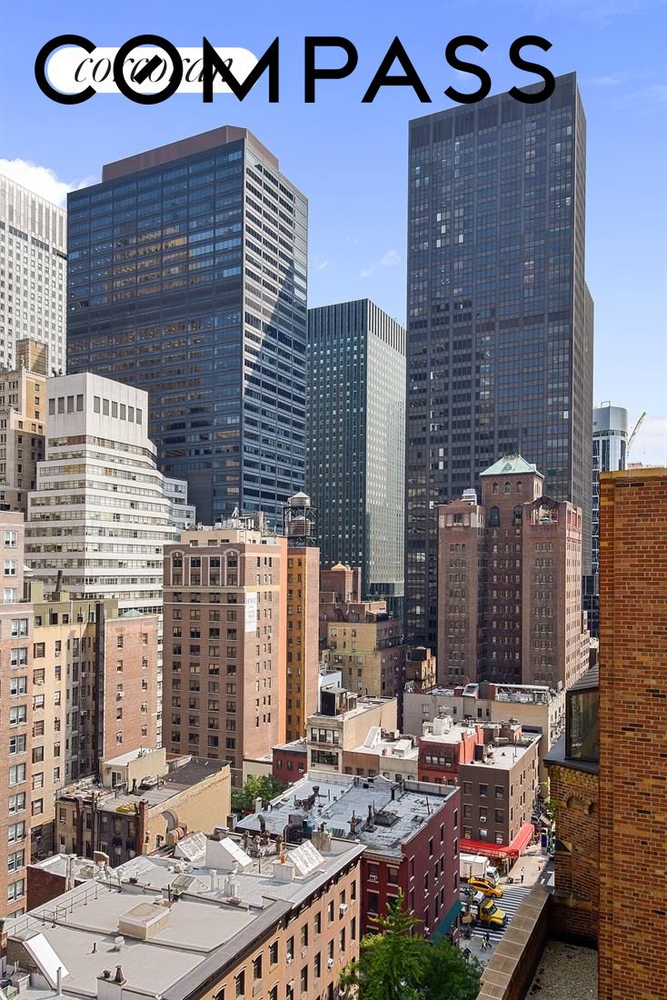 Manhattan city skyline viewed from above, with glass towers and dense rooftops.