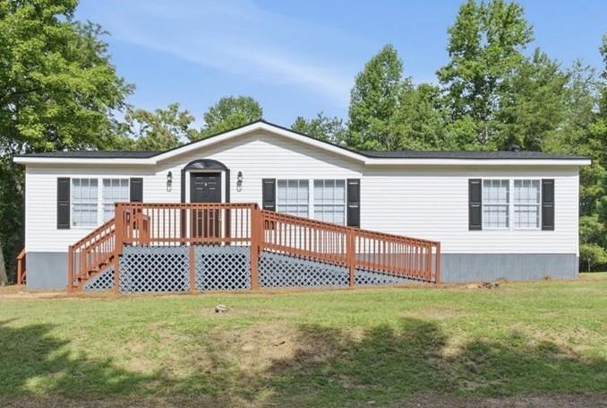 White single-story home with a raised wooden deck and ramp, viewed from the front.
