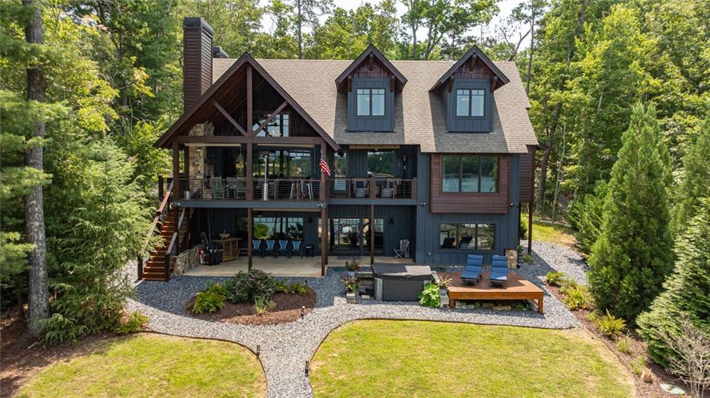 Wooded home with a covered two-story deck, hot tub, and gravel path.
