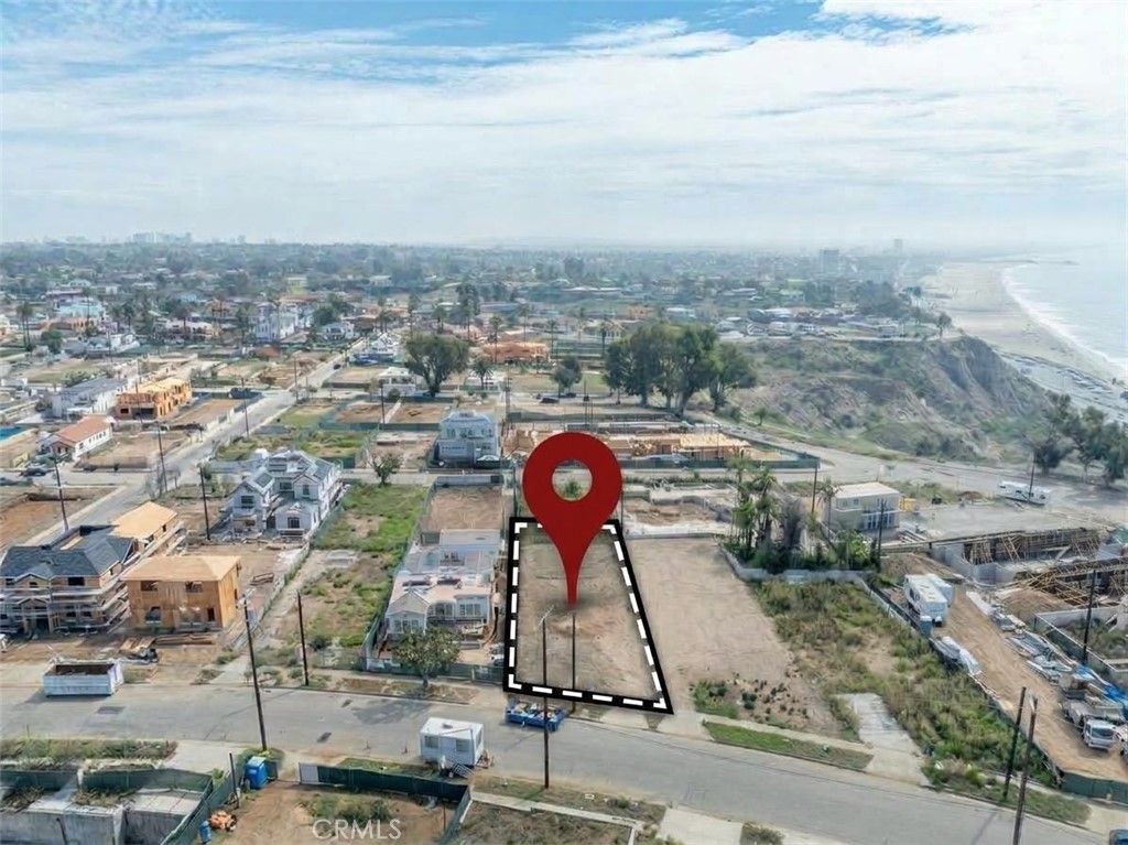 Vacant coastal lot outlined and marked with a red pin, with the ocean and beach nearby.