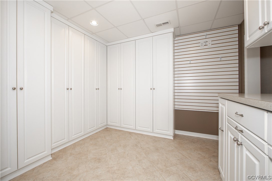 Built-in storage room with white cabinets, a slatwall panel, and a counter with drawers.